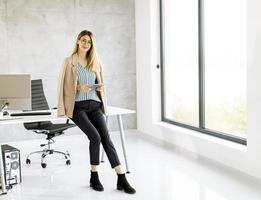 femme d'affaires assise sur le bord d'un bureau avec une tablette