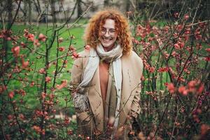 Naturel portrait de une caucasien gingembre femme avec taches de rousseur et frisé cheveux. elle est souriant et à la recherche à caméra. photo