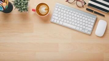 en bois bureau lieu de travail avec clavier, souris, stylo, monocle, carnet et tasse de café, Haut vue plat allonger avec copie espace. photo