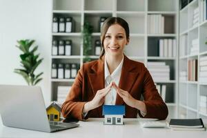 agent immobilier féminin utilise les mains pour protéger le toit rouge pour le concept d'investissement immobilier sur le commerce de la maison, achat au bureau au bureau photo