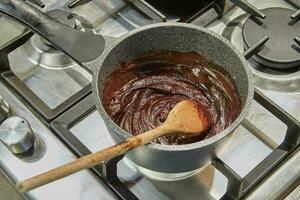 Chocolat est cuit dans casserole sur gaz le fourneau photo