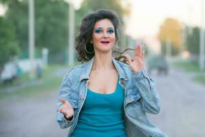 magnifique Jeune femme dans une denim veste avec brillant maquillage dans le style de le 80 sur le rue. photo