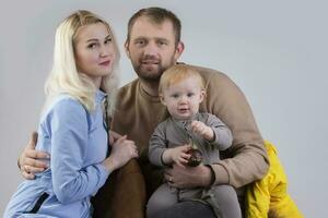 sur une gris Contexte famille de Trois gens maman papa et bébé. photo