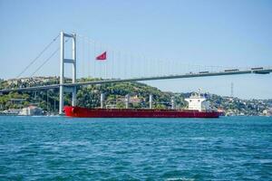 une cargaison navire voiles en dessous de une pont dans Istanbul sur une été et ensoleillé journée. photo