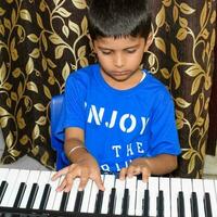 asiatique garçon en jouant le synthétiseur ou piano. mignonne peu enfant apprentissage Comment à jouer piano. enfant mains sur le clavier intérieur. photo