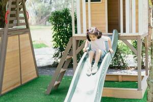 jolie fille asiatique sourire jouer sur la cour ou l'aire de jeux de l'école ou de la maternelle. activité estivale saine pour les enfants. petite fille asiatique grimpant à l'extérieur sur l'aire de jeux. enfant jouant sur une aire de jeux extérieure. photo