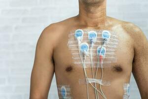 homme portant 24 heures électrocardiogramme moniteur dispositif sur le sien poitrine, électrodes rythme Holter surveillance et du sang pression moniteur système sur le poitrine de une homme. santé se soucier cœur maladie concept. photo