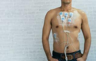 homme portant 24 heures électrocardiogramme moniteur dispositif sur le sien poitrine, électrodes rythme Holter surveillance et du sang pression moniteur système sur le poitrine de une homme. santé se soucier cœur maladie concept. photo