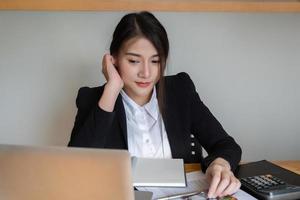 une femme d'affaires ou des comptables travaillent au bureau pour vérifier l'exactitude du compte à l'aide d'une calculatrice et d'un ordinateur portable photo