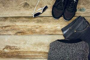 aux femmes Vêtements et accessoires gris chandail, jeans, ceinture, baskets, des lunettes de soleil, Jaune feuilles sur en bois Contexte. Haut voir. tonique image. photo