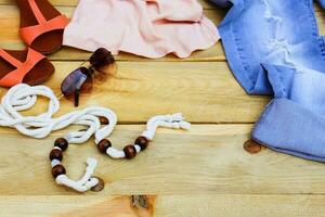 aux femmes été Vêtements et accessoires réservoir haut, jeans, des lunettes de soleil, ceinture, des chaussures sur en bois Contexte. photo