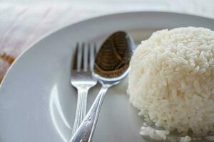 blanc riz avec cuillère et fourchette sur blanc plaque. le photo est adapté à utilisation pour nourriture arrière-plan, menu affiche et contenu médias.