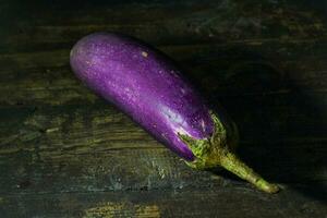 brillant violet Frais en bonne santé aubergines sur foncé en bois Contexte photo