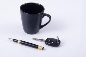 Tasse à café avec clé de voiture et stylo plume d'affaires sur fond blanc photo