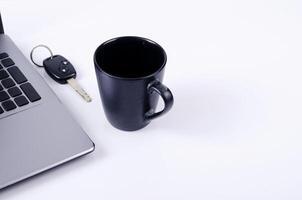 concept de technologie de vie avec tasse de café, clés de voiture et ordinateur portable sur fond blanc photo