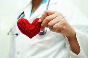 femme médecin asiatique tenant un coeur rouge pour la santé à l'hôpital. photo