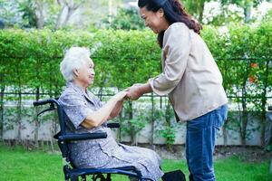 soignant Aidez-moi asiatique personnes âgées femme invalidité patient séance sur fauteuil roulant dans hôpital, médical concept. photo