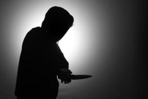 mystérieux homme portant noir sweat à capuche en portant une couteau à poignarder quelqu'un. crimes et criminalité concept photo