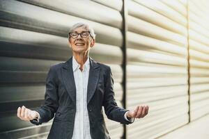 Extérieur portrait de mature femme d'affaires qui est méditer dans de face de entreprise bâtiment. photo