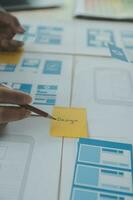 gros plan sur le développeur ux et le concepteur d'interface utilisateur remue-méninges sur la conception filaire de l'interface de l'application mobile sur la table avec le client breif et le code couleur au bureau moderne. agence de développement numérique créative photo