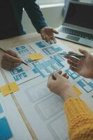 gros plan sur le développeur ux et le concepteur d'interface utilisateur remue-méninges sur la conception filaire de l'interface de l'application mobile sur la table avec le client breif et le code couleur au bureau moderne. agence de développement numérique créative photo