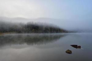 Paysage d'automne dans les montagnes avec des arbres se reflétant dans l'eau au lac de st ana roumanie photo