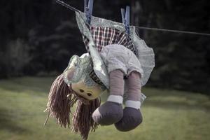 Concept de violence contre les enfants, poupée aux cheveux rouges abandonnée en robe accrocher sur une corde photo
