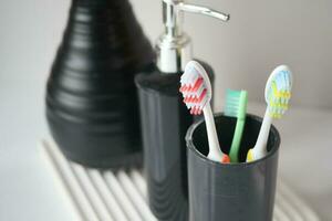 Brosses à dents colorées dans une tasse blanche contre un mur photo