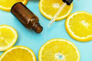 flacon en verre brun avec une pipette sérum à la vitamine c. huile essentielle et tranches d'orange. concept de santé et de beauté. photo