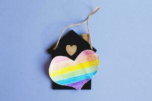 coeur sous la forme d'un drapeau lgbt à côté d'une maison de jouet miniature. photo