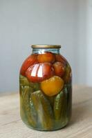 boîte gâtée de coutures de légumes. bocal en verre avec tomates et concombres marinés maison avec champignon blanc photo