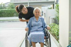 soignant Aidez-moi et se soucier asiatique personnes âgées femme patient séance sur fauteuil roulant à rampe dans allaitement hôpital, en bonne santé fort médical concept. photo