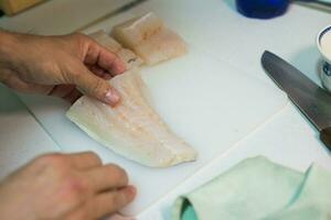 homme main en portant une Frais pièce de merlu pour cuisine photo