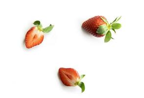 des fraises sur une blanc Contexte. un entier baie et deux moitiés de juteux fruit. composition dans le style de plat poser. photo
