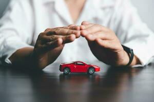 affaires femme main protéger rouge jouet voiture sur bureau. Planification à gérer transport la finance frais. concept de voiture Assurance entreprise, économie acheter - vente avec impôt et prêt pour Nouveau auto. photo