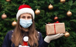 Portrait pf une femme portant bonnet de Noel et pull bleu en masque médical