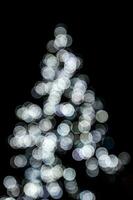 flou lumières éclairant le Noël arbre sur une noir Contexte photo