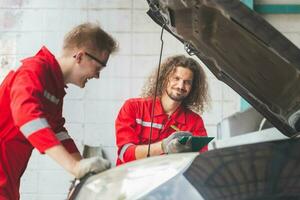 technicien équipe vérification moderne voiture à garage, Jeune caucasien voiture mécanicien avec une liste de contrôle, mécanique dans uniforme sont travail dans auto service, voiture réparation et entretien concepts photo