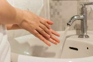 fermer de Jeune femme la lessive mains plus de évier dans salle de bains à maison. hygiène traitement concept photo