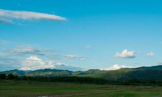 campagne paysage. riz champ et Montagne avec bleu nuageux ciel Contexte. photo