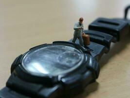 bogor, Indonésie - 2018. une miniature figure de un Bureau ouvrier en marchant sur une montre. photo