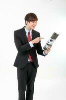 Jeune intelligent Beau asiatique homme affaires Bureau portant costume attacher sur blanc Contexte en train de lire livre magazine main sur menton concentrer photo