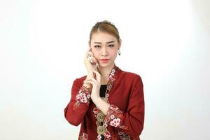 asiatique femme traditionnel rouge bordeaux kebaya partager sur blanc Contexte posant main sur joue photo