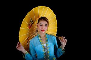 asiatique femme dans tractionnel kebaya porter parapluie sur noir Contexte photo