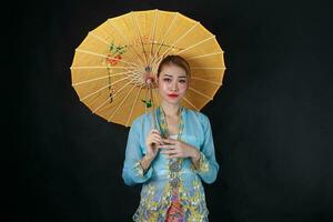 asiatique femme dans tractionnel kebaya porter parapluie sur noir Contexte photo