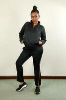 asiatique Indien femme portant noir Piste costume pose hanche saut style moderne froussard asiatique Indien femme portant Piste costume pose hanche saut style moderne froussard photo