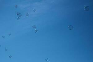 délicat fragile savon bulles en volant contre le Contexte de une bleu sans nuages ciel sur une été jour, photo