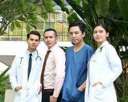 Sud est asiatique Jeune malais chinois homme femme médical médecin stéthoscope tablier groupe supporter pose sur de soi photo