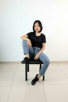 Jeune attrayant Sud est asiatique femme pose visage expression émotion sur blanc Contexte asseoir sur chaise photo