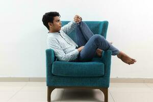 une Jeune Sud est asiatique asseoir pose Regardez pense travail étude émotion sentiments sur une bleu Célibataire canapé. il est adhd et autistique photo